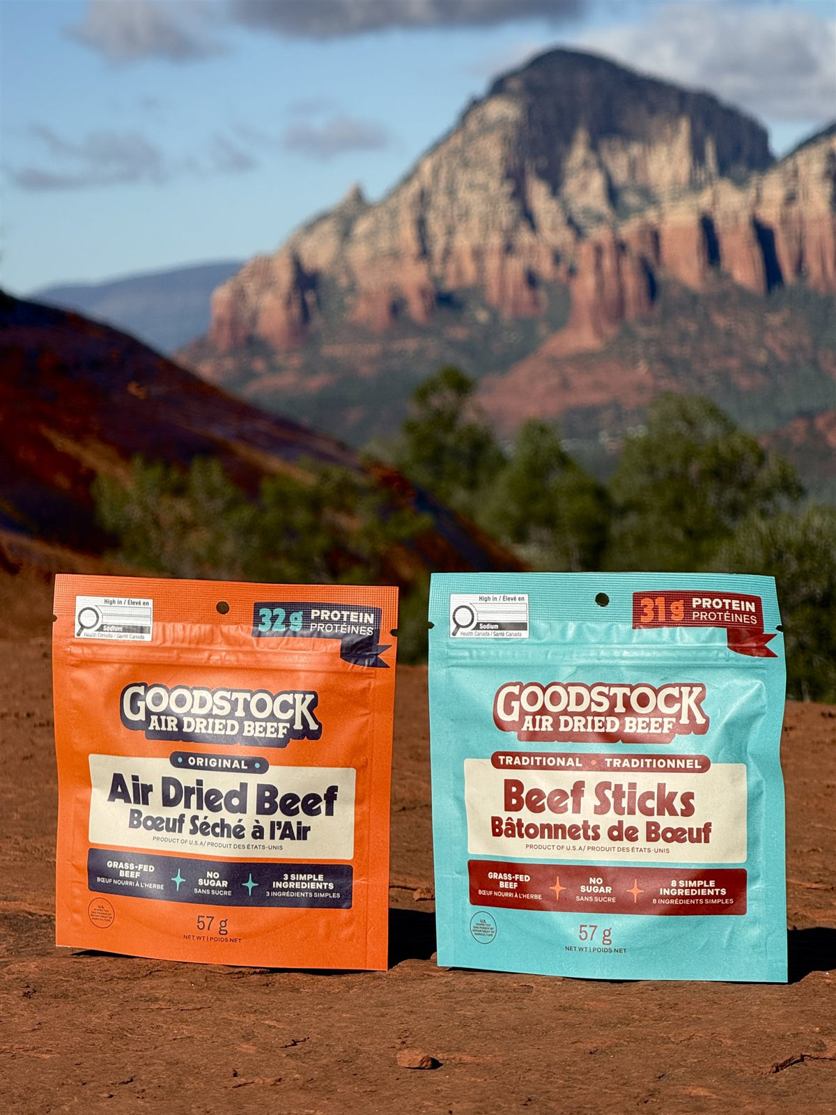 Goodstock Original Air Dried Beef and Traditional Beef Sticks pouches on red rock with mountains behind